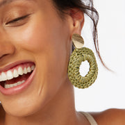 Smiling brunette wearing a pair of hand crocheted statement front facing hoop style statement earrings in olive green and gold