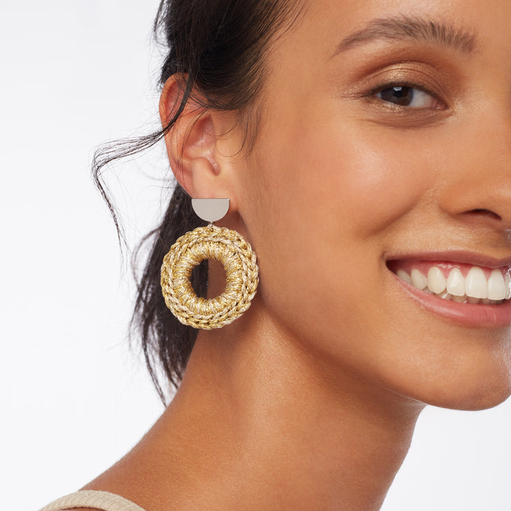 Brunette smiling wearing a pair of front facing hand crocheted hoops in mixed metal tones, with silver tone semi circle earring posts.