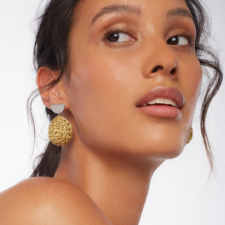 Brunette wearing a pair of earrings. Hand crocheted domes in sand gold under silver tone semi circle earring posts.