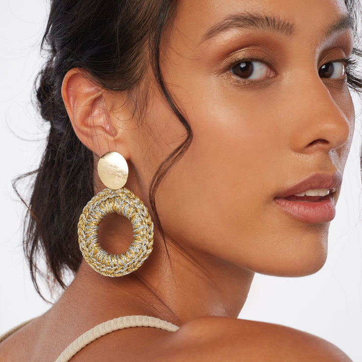 Brunette wearing a pair of front facing statement hand crocheted hoops in mixed metal tones, with oval gold tone earring posts.