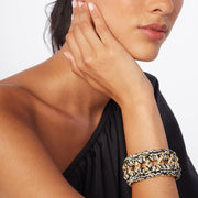 Woman's wrist wearing chunky hand crocheted bracelet where  gold tone chain meets black, silver and gold tones.
