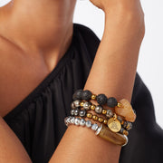 Wrist of a woman wearing a stack of 4 bracelets in mixed metal tones, carnelian, lava, hematite, ceramic and acrylic horn-like beads.