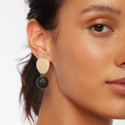 Brunette wearing a pair of earrings in gold and black tones with oval gold plated posts